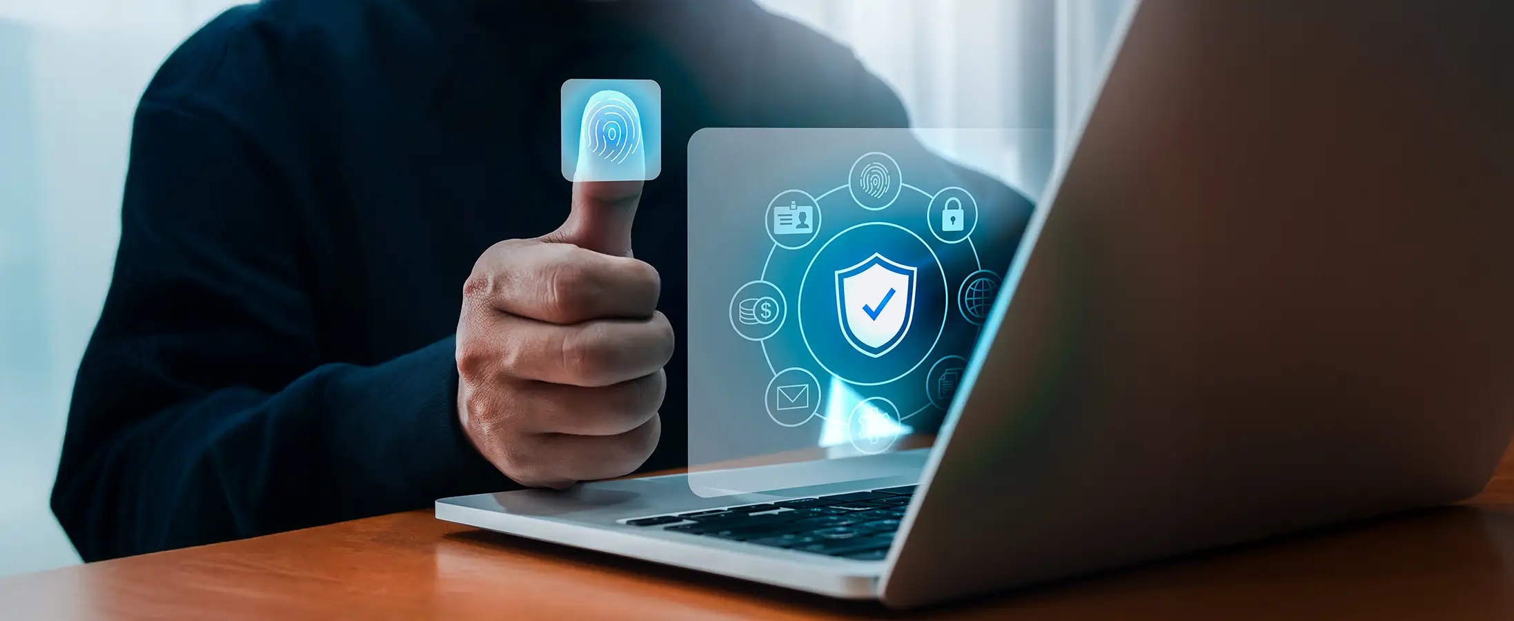 A man is touching a graphic of the thumb print while working on a laptop