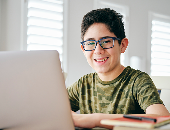 A young boy smiling while using a computer.